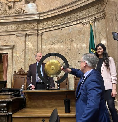 Rep. Bill Ramos, D-Issaquah, takes a swing at a gong, a less-than-conventional presence on the House of Representatives floor, after Democrat Tacoma Reps. Jake Fey and Sharlett Mena just took their turns Sunday.  (Elena Perry/THE SPOKESMAN-REVIEW)