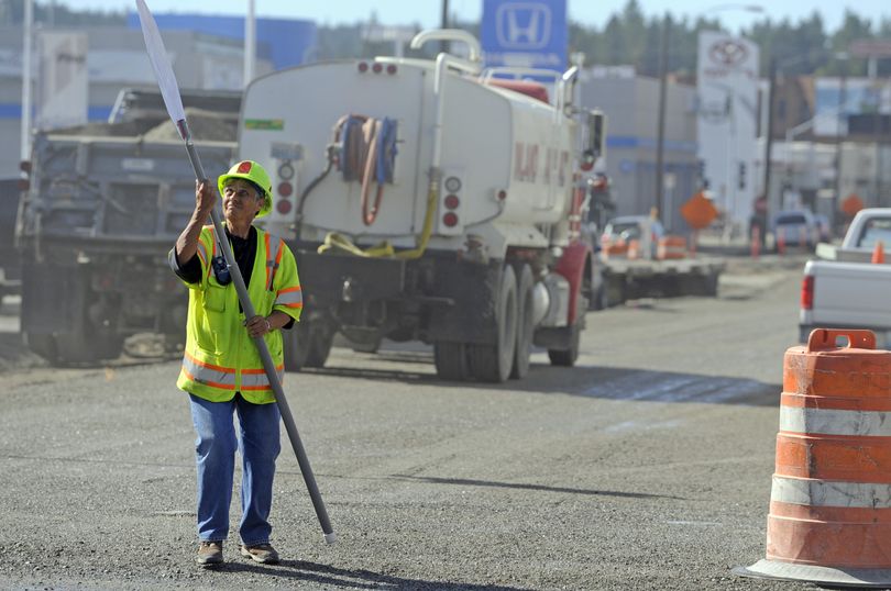 Pat Rairdan checks her sign before letting cars through the road construction at Second Avenue and Monroe Street on Monday.  (Jesse Tinsley)