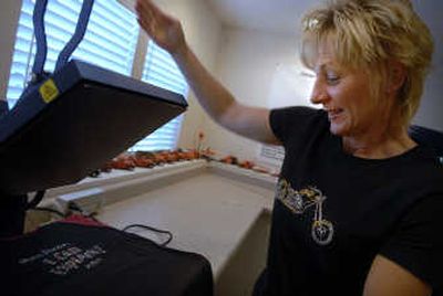 All In One Logos owner Lynn Messmer  uses a heated press to apply rhinestones to a T-shirt. Messmer creates logos and will print them on signs, apparel, buttons and magnets, among other items. 
 (Holly Pickett / The Spokesman-Review)