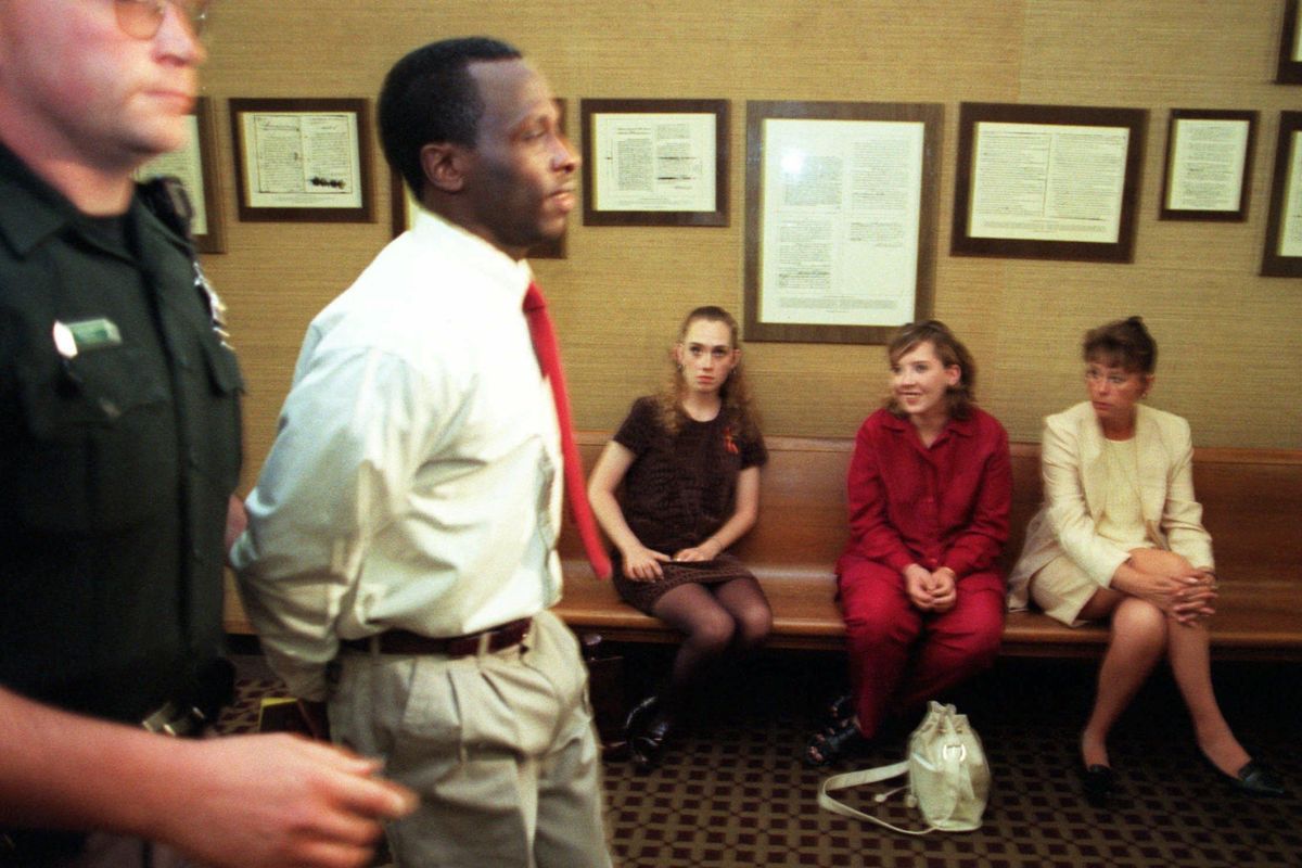 Venus Shaver, in red, watches Spokane County sheriff’s deputies lead Dwayne Woods back to jail during a break inhis trial in June 1997. The previous year, Shaver had survived an attack by Woods that left her seriously injured. Woods was later sentenced to die for killing her sister, Telisha Shaver, and a friend, Jade Moore. Seated to  Shaver’s left is a friend. To her right is victims advocate Gwen Cordova. (Christopher Anderson / The Spokesman-Review)