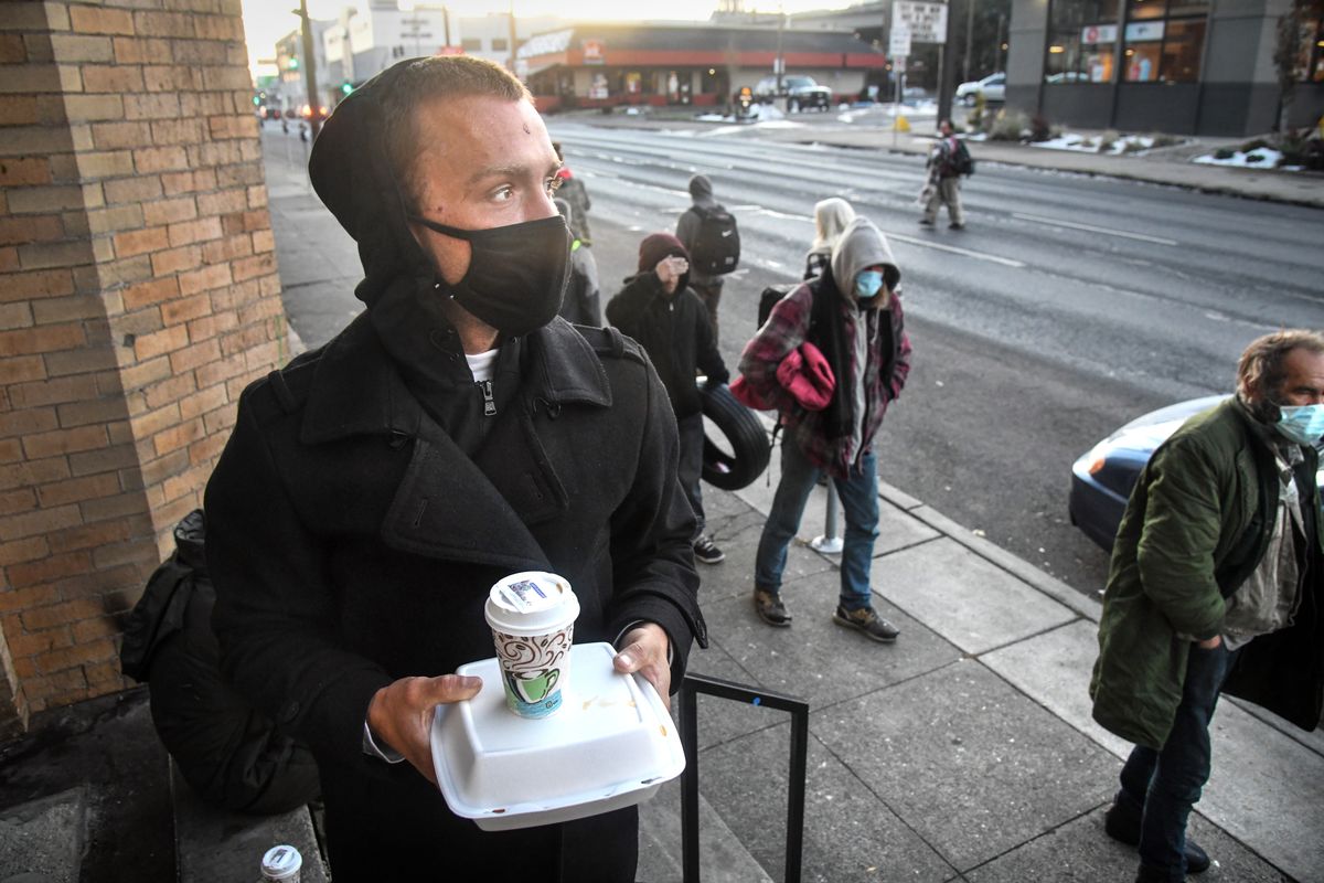 Michael Brackett, 29, picks up his breakfast, which included applesauce, a sandwich, a cheese stick and a drink, provided by Shalom Ministries, Thursday morning, Oct. 29, 2020, at New Community Church in downtown Spokane.  (DAN PELLE/THE SPOKESMAN-REVIEW)