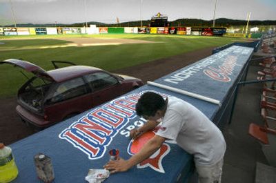 Ruben Marcilla paints the Spokane Indians logo on top of their dugout at Avista Stadium last Tuesday. Marcilla has been hand-painting all the signs on the outfield walls and atop the dugouts for years. His favorite is a Pepsi advertisement. 
 (Photos by Christopher Anderson / The Spokesman-Review)