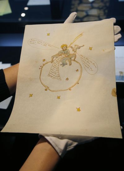 A staff member of the auction house Artcurial displays a watercolor illustration by Antoine de Saint-Exupery, done around 1942, in Paris, France, Friday, June 15, 2018. The illustration showing a likeness of Saint-Exupery's renowned Little Prince atop a globe, adorning an anguished love letter, has sold at auction for $289,460. (Michel Euler / Associated Press)