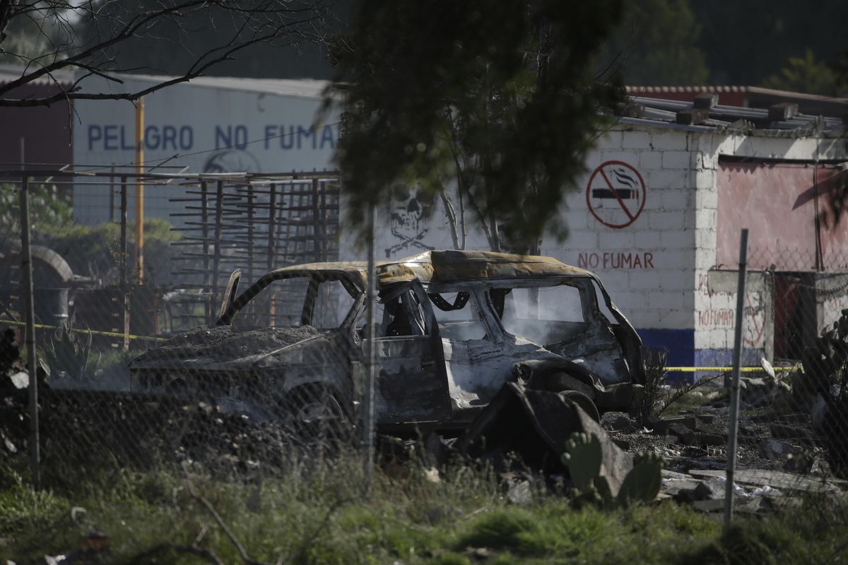 A burned car smolders Thursday, July 5, 2018, at the site where several fireworks workshops blew up in Tultepec, Mexico. More than a dozen people were killed and at least 40 injured when a series of explosions ripped through fireworks workshops in a town just north of Mexico City. (Moises Castillo / AP)