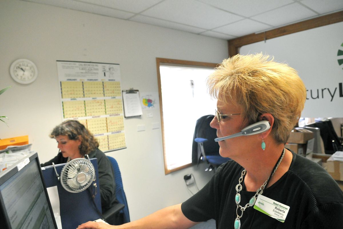 Roberta Eckelberry, right, a customer service representative for CenturyLink, formerly called Qwest, talks with a customer at the company’s regional office in Cheney. At left is Terri Marlin. Although it’s been decades since a phone operator had to use patch cords and patch bays to connect phone calls, people like Eckelberry still talk with customers every day and resolve problems with their phones and phone bills. (Jesse Tinsley)