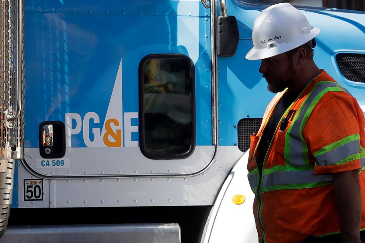 FILE - In this Aug. 15, 2019, file photo, a Pacific Gas & Electric worker walks in front of a truck in San Francisco. Pacific Gas & Electric has agreed to pay more than $55 million to avoid criminal prosecution for two major wildfires started by its aging equipment in 2019 and 2021, prosecutors announced.  (Jeff Chiu)