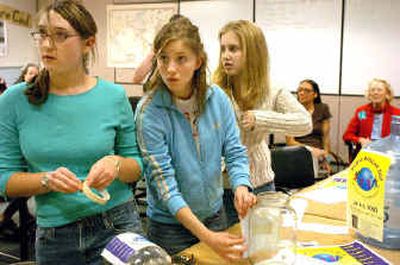 From left, Maggie Steele, Jenna Betts and Kayla Leitzke of the Lake City High Human Rights Club listen to directions while decorating containers for World Dollar Day.
(Jesse Tinsley / The Spokesman-Review)