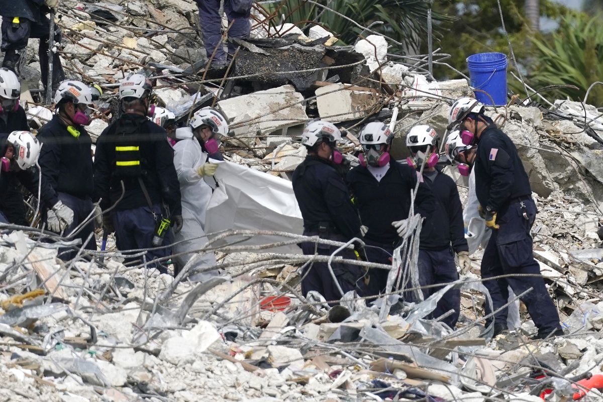 Rescue workers use a tarp for recovered remains at the site of the collapsed Champlain Towers South condo building, Monday, July 5, 2021 in Surfside, Fla. The remaining structure was demolished Sunday, which partially collapsed June 24. Many people remain unaccounted for.  (Lynne Sladky)