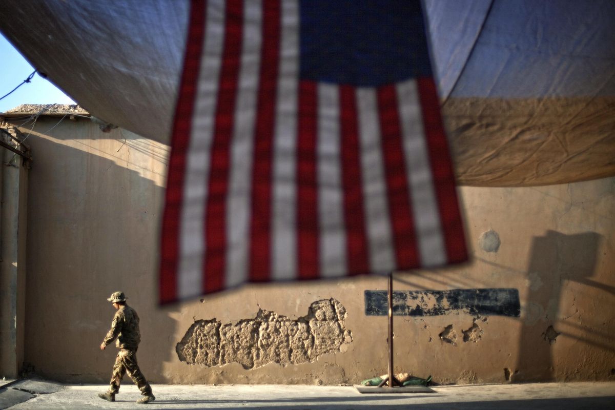 In this Sept. 11, 2011 photo, a U.S. Army soldier walks past an American Flag hanging in preparation for a ceremony commemorating the tenth anniversary of the 9/11 attacks, at Forward Operating Base Bostick in Kunar province, Afghanistan. The final phase of ending America