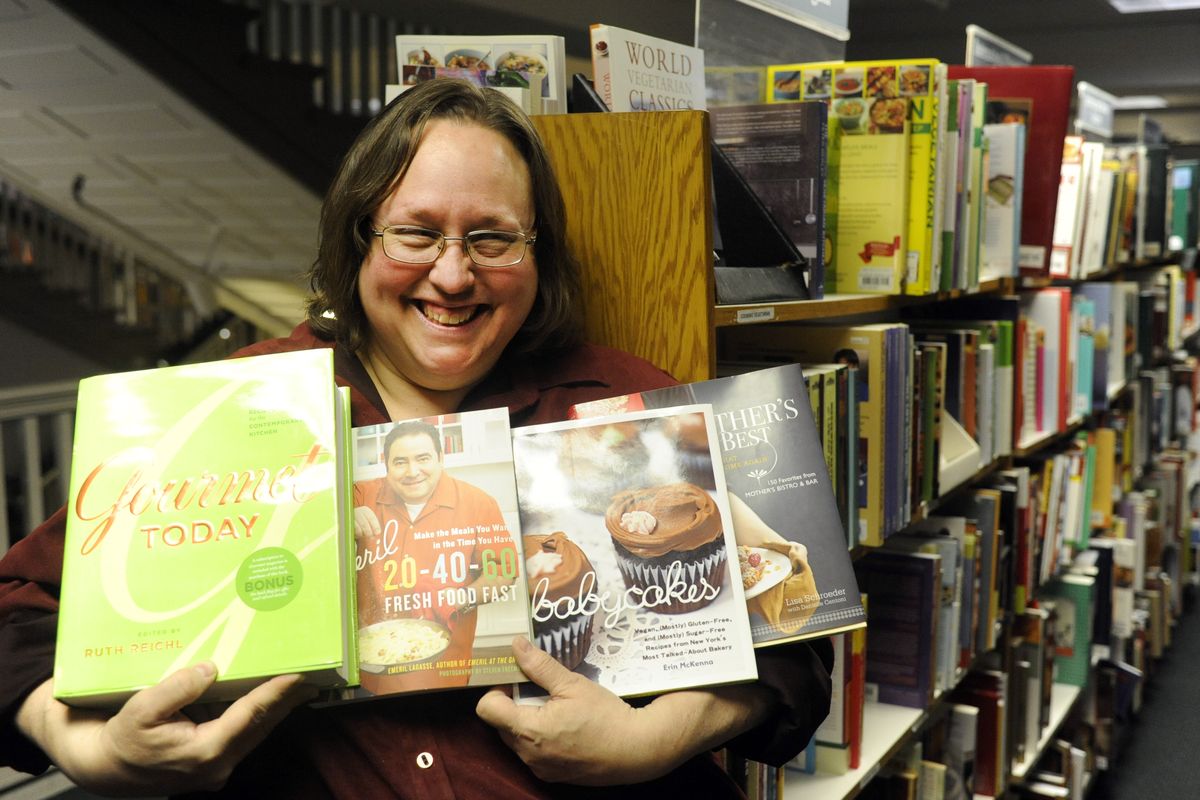 Cathy Routen, standing in the cookbook aisle of Auntie’s Bookstore, holds some of her recommendations for cookbook gifts this holiday season. (Jesse Tinsley)