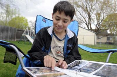 
Kevin Tsuchida, 10, of Spokane, looks at    photo albums of his trips to Washington, D.C. He is a representative of the Epilepsy Foundation. 
 (Jesse Tinsley / The Spokesman-Review)