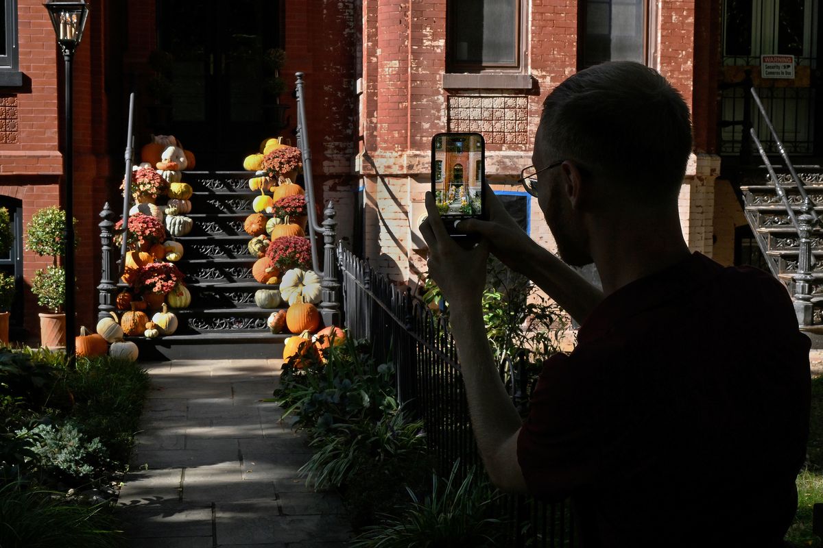 Passerby Evan Feldberg-Bannatyne is one of many who stop to photograph Josh Young’s pumpkin-covered stoop in Washington, D.C.  (Michael S. Williamson/The Washington Post)
