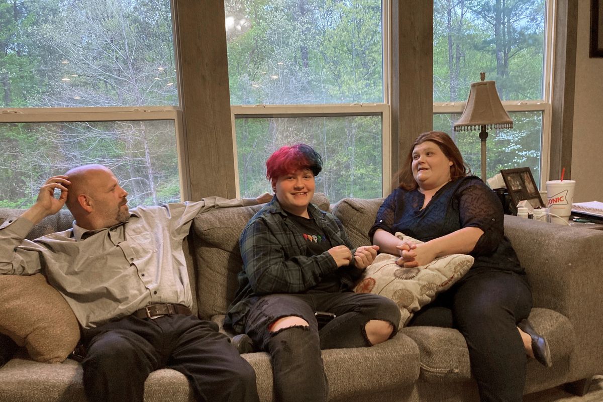 FILE - In this April 15, 2021 file photo, Andrew Bostad, center, talks with his mother, Brandi Evans and stepdad Jimmy Evans at their home in Bauxite, Ark. Andrew is one of hundreds of transgender youth in Arkansas who could have their hormone therapy cut off under a new state law banning gender confirming treatments for minors. A federal judge on Wednesday, July 21, has temporarily blocked Arkansas
