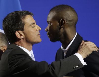 Lassana Bathily kisses French Prime Minister Manuel Valls, left, Tuesday. (Associated Press)