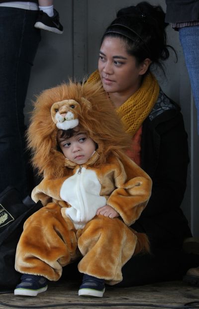 Checking out the competition: Almost 2 and dressed as an African lion, Hunter Knight keeps an eye on other costumed kids while onstage with his mother, Kaila, during the fifth annual Halloween costume contest Sunday at the Olympia Farmers Market. Popular costume themes included a variety of fairies and ninja warriors, sprinkled with a Darth Vader or two. (Associated Press)