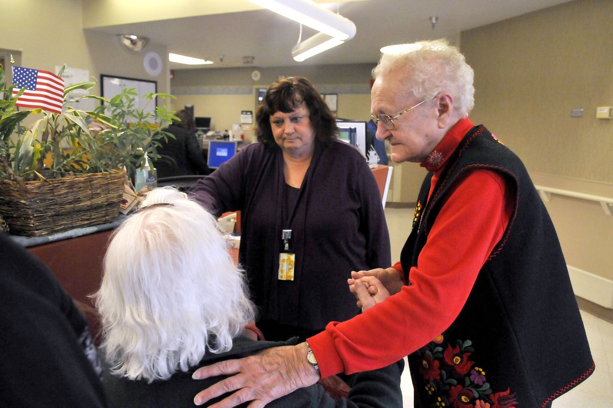 Lee Hutchison, right, comforts a patient’s wife, left, along with Cindy Shepard, health unit coordinator, at the Spokane Veterans Affair Medical Center on Feb. 6. Hutchison, who was named January employee of the month, is the first volunteer to get the award. (Jesse Tinsley)