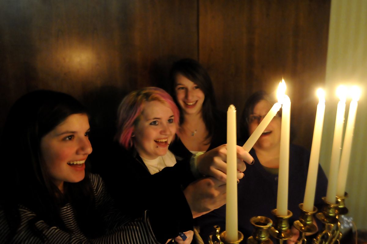 Molly Rubens, 14, Rachael Cowen, 16, Amalia Williams, 17, and Suzanne Rubens help light a stubborn candle on the menorah at Temple Beth Shalom on Tuesday.  (Jesse Tinsley)