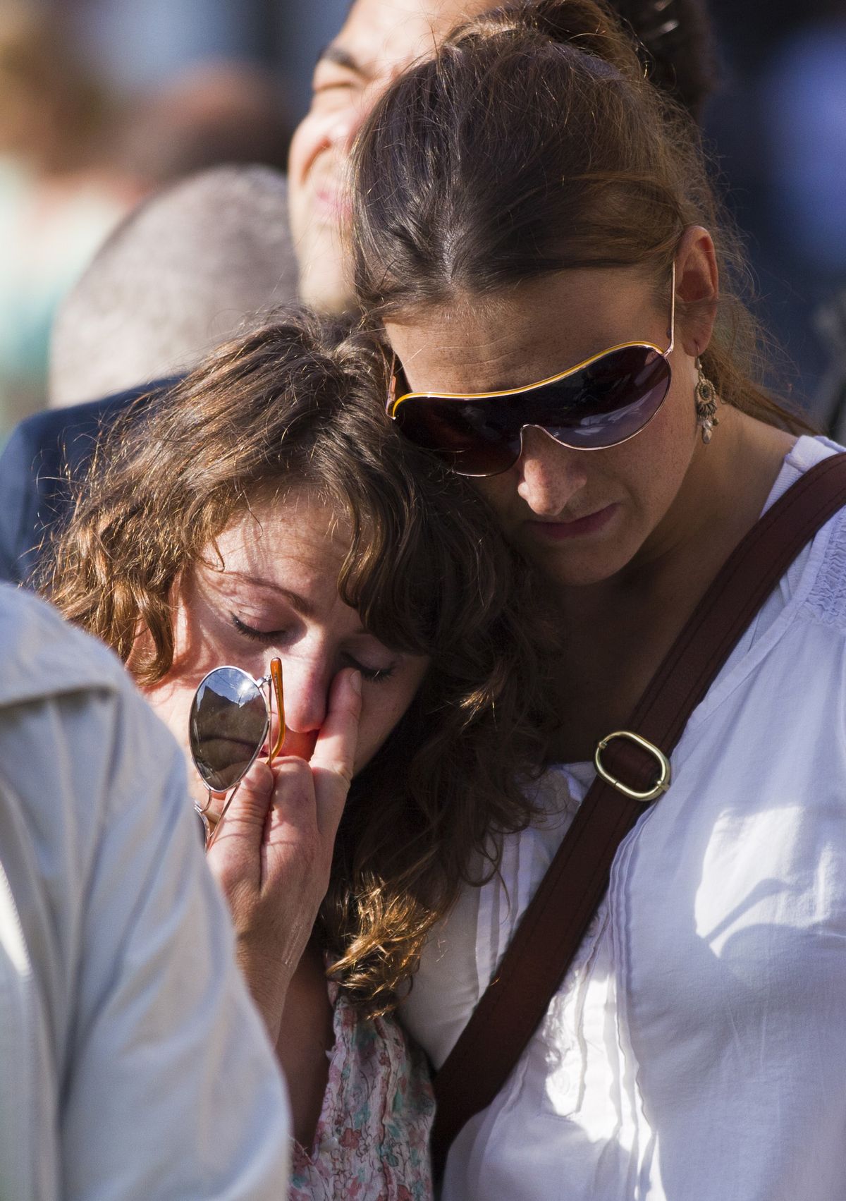 Women console each other during a vigil Saturday for victims of Friday