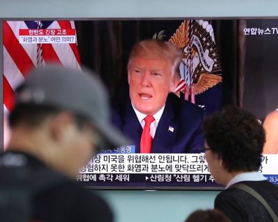 People walk by a TV screen showing a local news program reporting with an image of U.S. President Donald Trump at the Seoul Train Station in Seoul, South Korea, Wednesday, Aug. 9, 2017. North Korea and the United States traded escalating threats, with President Donald Trump threatening Pyongyang 