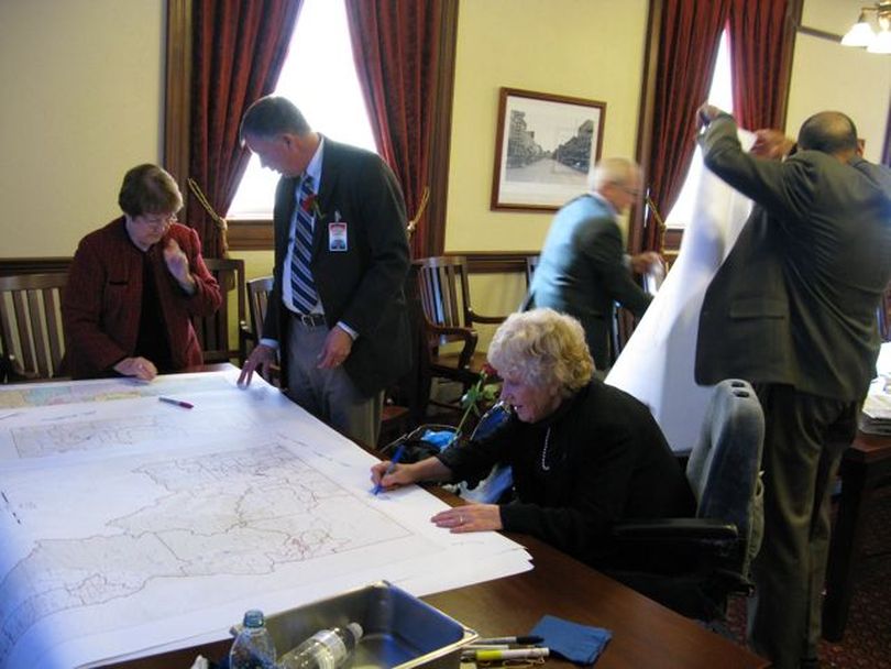 Idaho redistricting commissioners sign commemorative copies for each other of the legislative district map they adopted on a unanimous, 6-0 vote. (Betsy Russell)