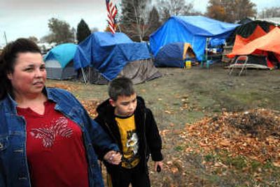
Christina DesChamps clutches the hand of her son Nicholas, 9, as they walk past a homeless camp  on their way home from Stevens Elementary in Spokane on Wednesday.  DesChamps won't allow her son to play outside anymore  because of the growing camp near their backyard. 
 (Brian Plonka / The Spokesman-Review)