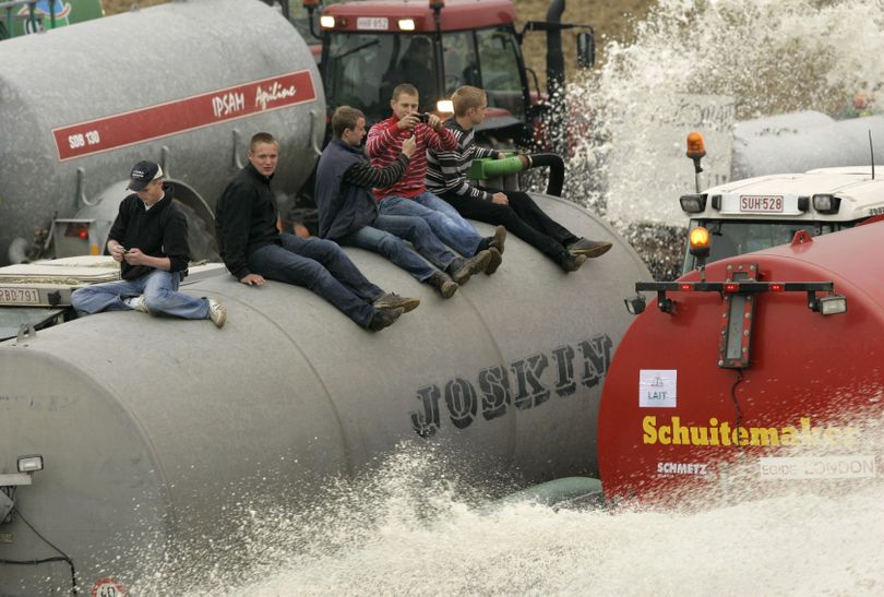 Men sit on top of a tank as farmers spray milk onto a field in Ciney, Belgium. (The Spokesman-Review)