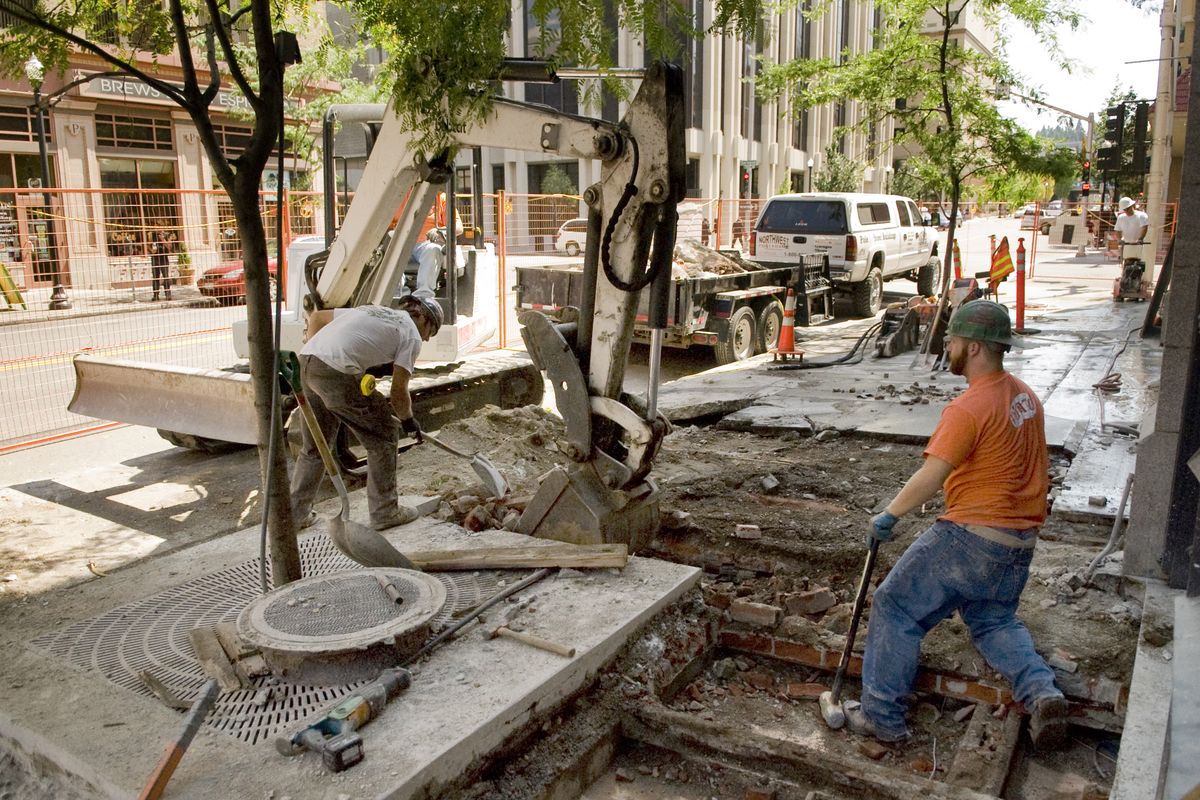 Nick Hagen, left, and Casey Britton, construction workers with Walt Worthy Enterprises, tear out the old sidewalks around the Hotel Lusso on Wednesday. (Colin Mulvany / The Spokesman-Review)