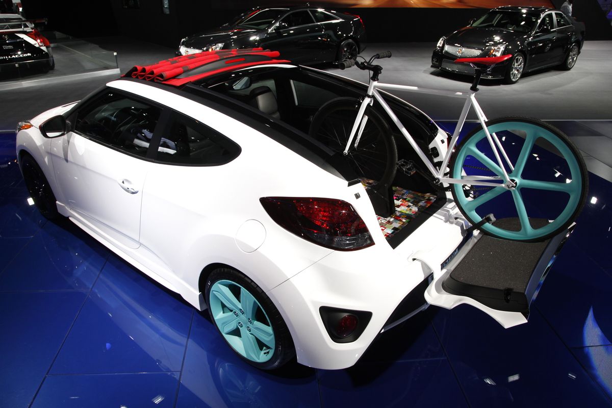 A bicycle is perched out the rear and rooftop of a Veloster coupe at the North American International Auto Show. Bikes are sharing the floor at the auto show along with the latest cars, trucks and concept vehicles. (Associated Press)