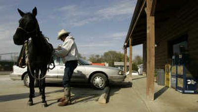 
Bill Inman looks for a place to tie up Blackie as he stops to eat at a restaurant in Fredonia, Kan., on Nov. 2. Inman is riding the horse from Oregon to North Carolina. He wants to call attention to a part of rural America he says gets overlooked in most daily news reports. Associated Press photos
 (Associated Press photos / The Spokesman-Review)