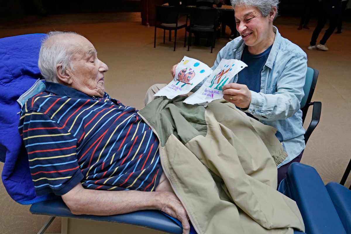 Melvin Goldstein, 90, glances at pictures of birds, left, and a fish, his 13-year-old granddaughter drew for him as a gift as his daughter Barbara Goldstein shares them during a family visit on March 28 inside the Hebrew Home at Riverdale in New York.  (Kathy Willens)