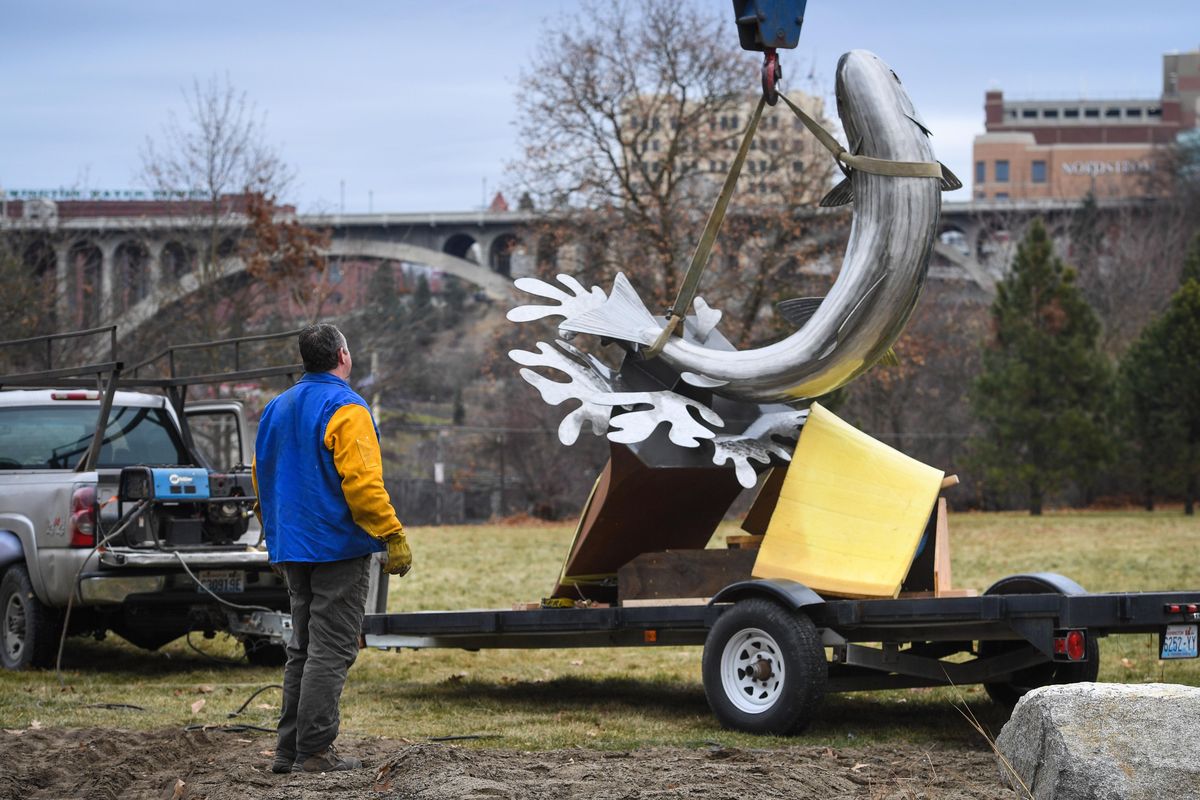 In the shadow of the Monroe Street Bridge, artist Chris Anderson hooks up his 12-foot sculpture Redband Rising from his trailer to be placed by crane in Redband Park, Wednesday, Dec. 4, 2019, in Spokane, Wash. (Dan Pelle / The Spokesman-Review)