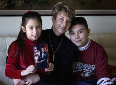 
Tracy Ferrez sits with her son Riko, 11, right, and her daughter Aitanna, 8. She and her husband Chris will be apart today since he is finishing a tour in Hawaii. Aitanna holds a photo of her parents who have been together for 14 years. 
 (Liz Kishimoto / The Spokesman-Review)