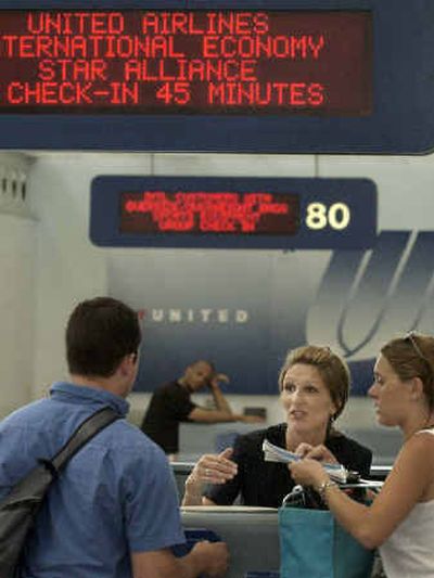 A United Airlines gate agent assists travelers at Chicago's O'Hare International Airport on Tuesday. Employees at United are bracing for the prospect of more sacrifices after the carrier's quest for federal assistance failed.
(Associated Press / The Spokesman-Review)