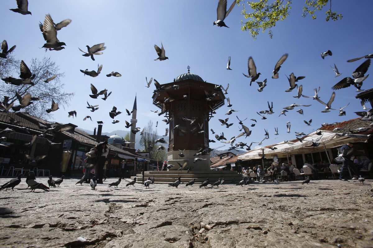 Birds fly around the Sebilj fountain on the central square in Sarajevo, Bosnia-Herzegovina, a popular stop for tourists. (Associated Press)