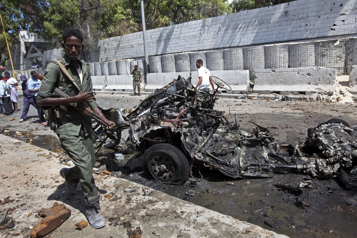 In this March 24, 2017, file photo, Somali soldiers walk near the wreckage of a car bomb attack in Mogadishu, Somalia. (Farah Abdi Warsameh / AP)