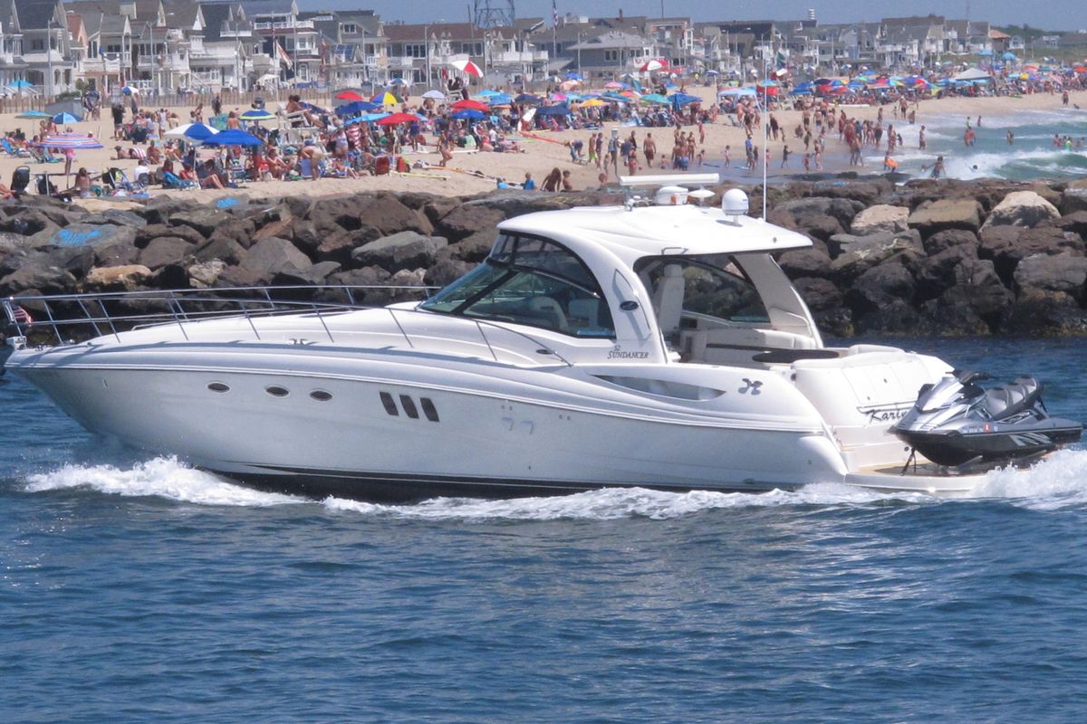 A yacht cruises through the Manasquan Inlet as a large crowd fills the beach in Manasquan, N.J. on June 28, 2020. With large crowds expected at the Jersey Shore for the July Fourth weekend, some are worried that a failure to heed mask-wearing and social distancing protocols could accelerate the spread of the coronavirus.  (Wayne Parry)
