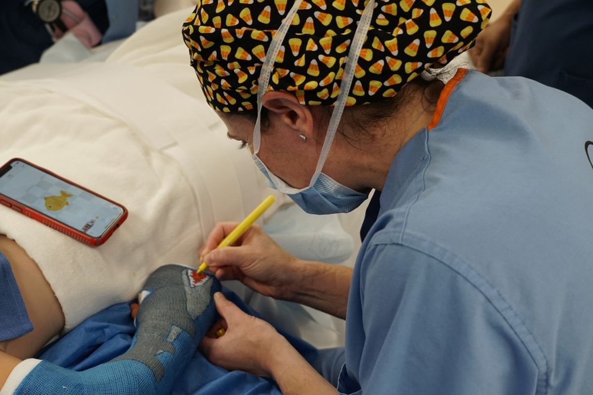Pediatric orthopedic surgeon Felicity Fishman adds some finishing touches to a shark swallowing a fish that one of her patients requested on his cast.  (Shriners Children