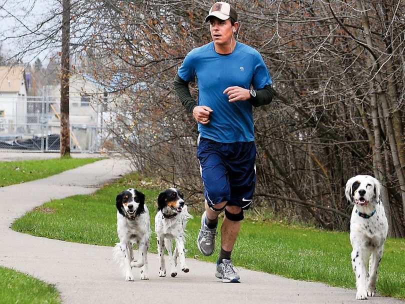 Ben Laster runs with his three dogs, from left, Penny, Daisy-Nay, and Chowdie, along Woodland Avenue in Kalispell, Mont. on May 3, 2011. Laster, 29, works as a wilderness instructor for the Wilderness Treatment Center, which counsels troubled youths by exposing them to outdoor experiences.  (Associated Press)