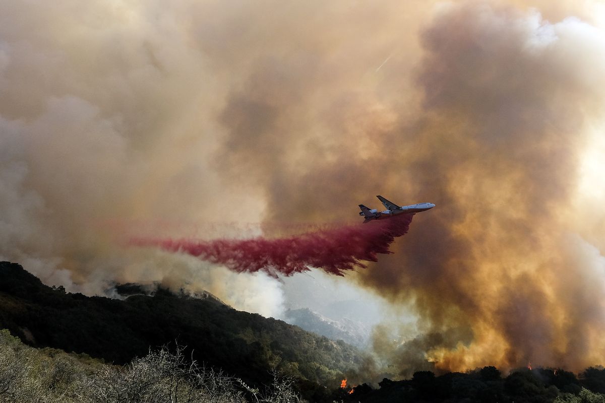 An air tanker drops retardant on a wildfire Wednesday, Oct. 13, 2021, in Goleta, Calif. A wildfire raging through Southern California coastal mountains threatened ranches and rural homes and kept a major highway shut down Wednesday as the fire-scarred state faced a new round of dry winds that raise risk of flames. The Alisal Fire covered more than 22 square miles (57 square kilometers) in the Santa Ynez Mountains west of Santa Barbara.  (Ringo H.W. Chiu)