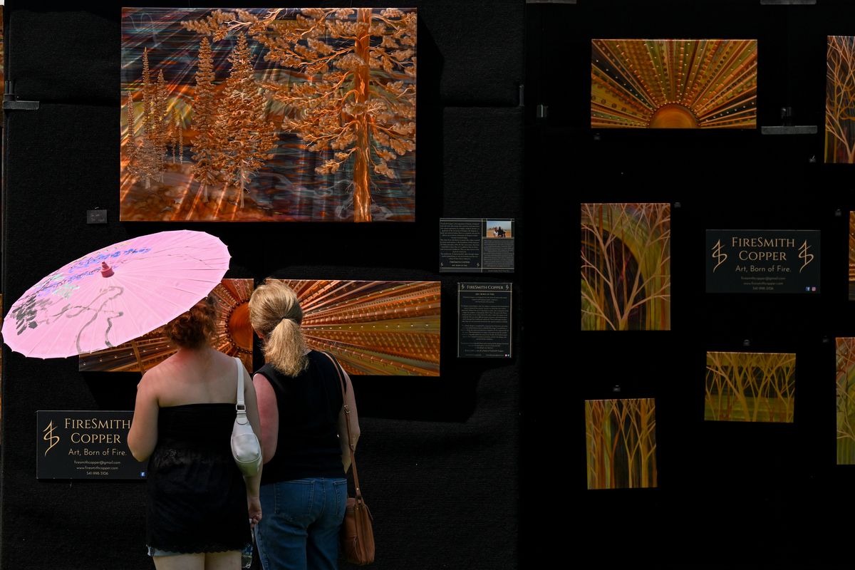 Art on the Green goers check out the flame-painted copper artwork of FireSmith Copper on Friday on NIC’s campus in Coeur d’Alene.  (Tyler Tjomsland/The Spokesman-Review)