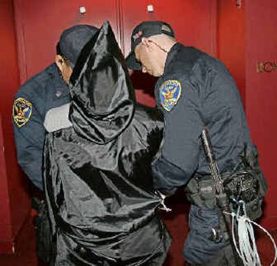 
Police detain a protester who disrupted Rice's speech. At least two protesters stood wearing black robes and hoods, an apparent reference to U.S. abuse of detainees at Iraq's Abu Ghraib prison. 
 (The Spokesman-Review)