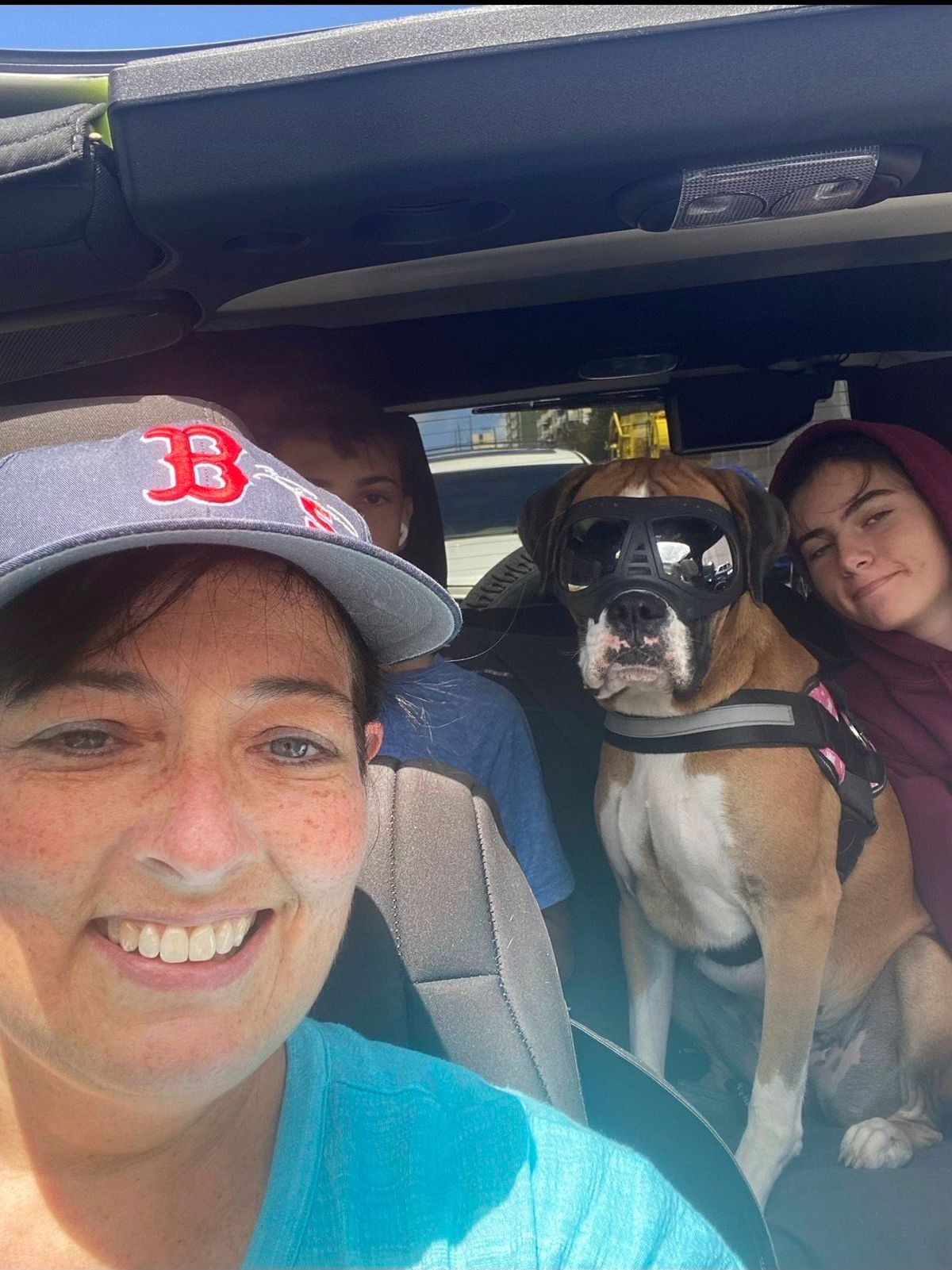 This 2021 photo provided by Cheri Burness shows Burness and her family, including dog Lilikoi, in car in Honolulu. Hundreds of military families living near Pearl Harbor have complained of stomach pain, nausea and other health ailments amid concerns the Navy