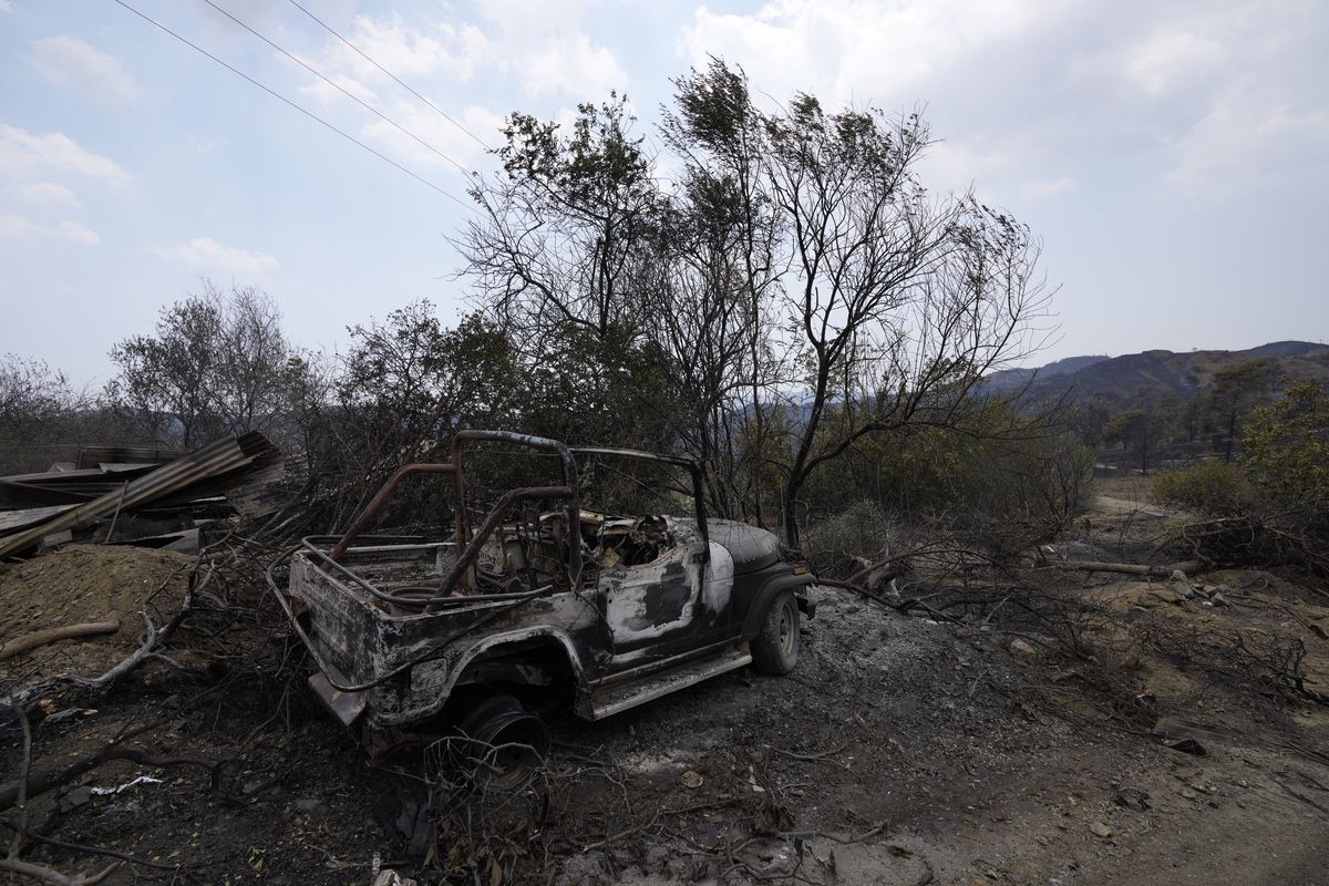 A burned car is seen on Troodos mountain, in Ora village, southwestern Cyprus, Sunday, July 4, 2021. Cyprus search crews discovered the bodies of four people outside a fire-swept mountain village on Sunday in what a government minister called the "most destructive" blaze in the east Mediterranean island nation