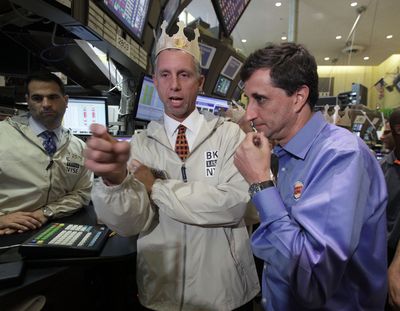 Burger King Corp. CEO Bernardo Hees, right, talks with specialist Donald Himpele, center, after his company's shares began trading on on the floor of the New York Stock Exchange on Wednesday. (Associated Press)
