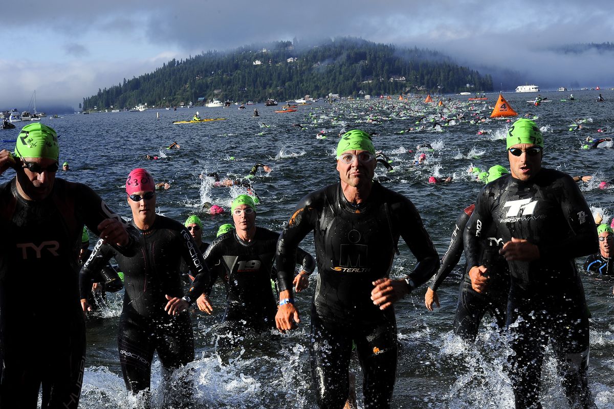 Competitors emerge from the waters of Lake Coeur d’Alene after the 2.4-mile swim to begin Ironman Coeur d’Alene on Sunday. (Tyler Tjomsland)