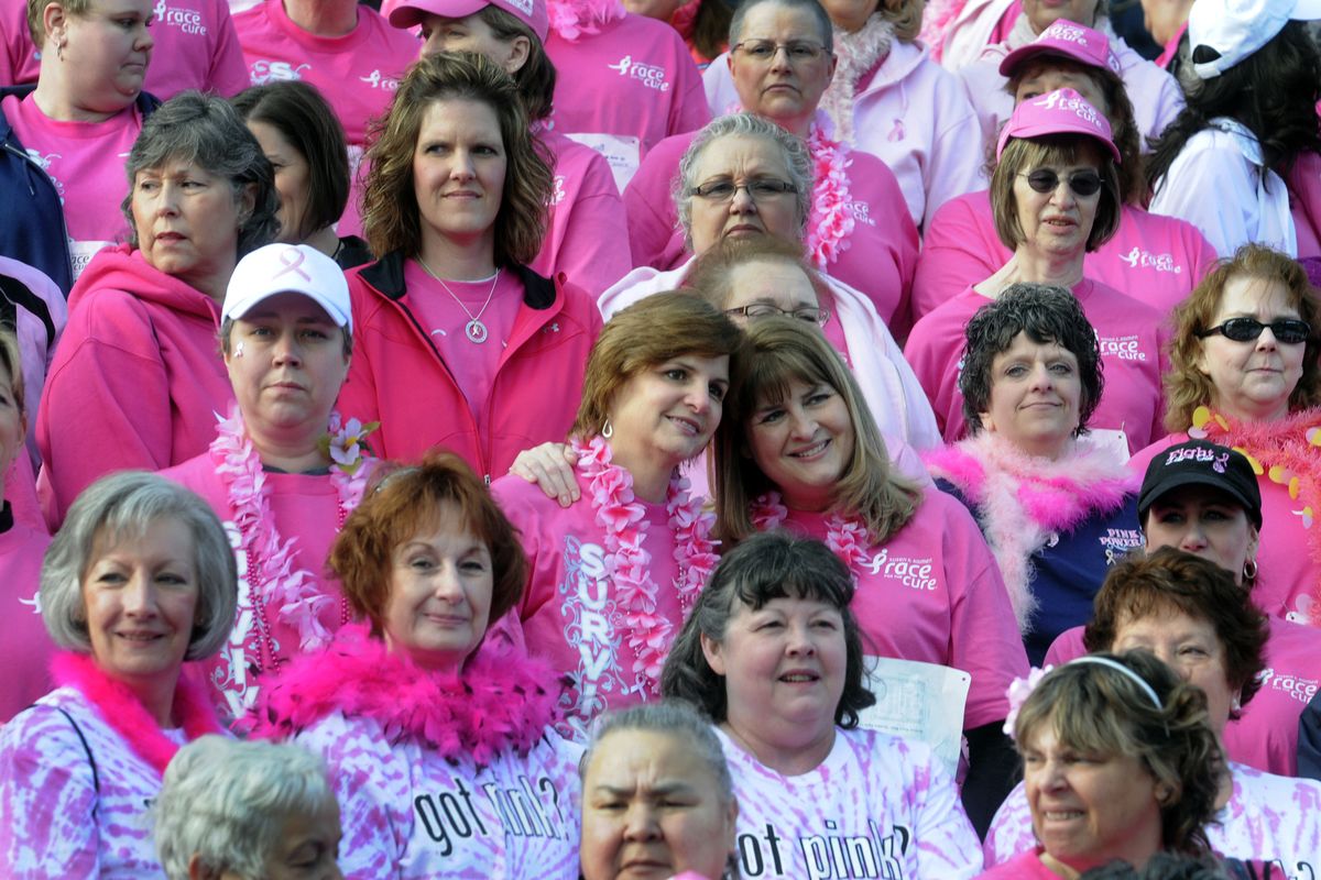Sisters Debbie Diettert, of Spokane, and Cheryl Troutwine, of Missoula, pose for a family member during the survivors photo before the race. (J. Bart Rayniak)