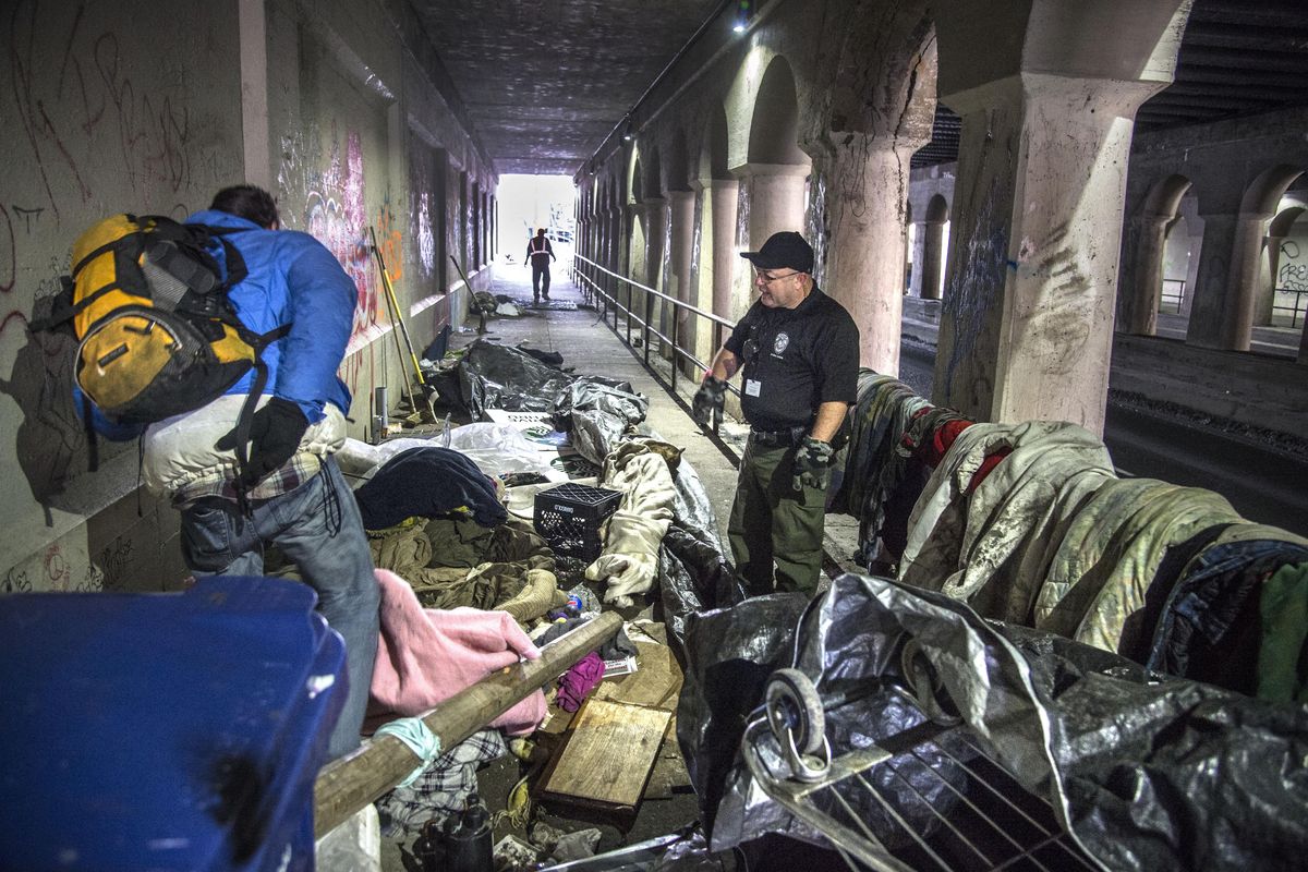Spokane County Detention Services officer Bobby McGowan asks Ricky Griffis to leave his camp beneath the railroad viaduct on Browne Street near Pacific Avenue so inmates could clean up the area. (Dan Pelle / The Spokesman-Review)