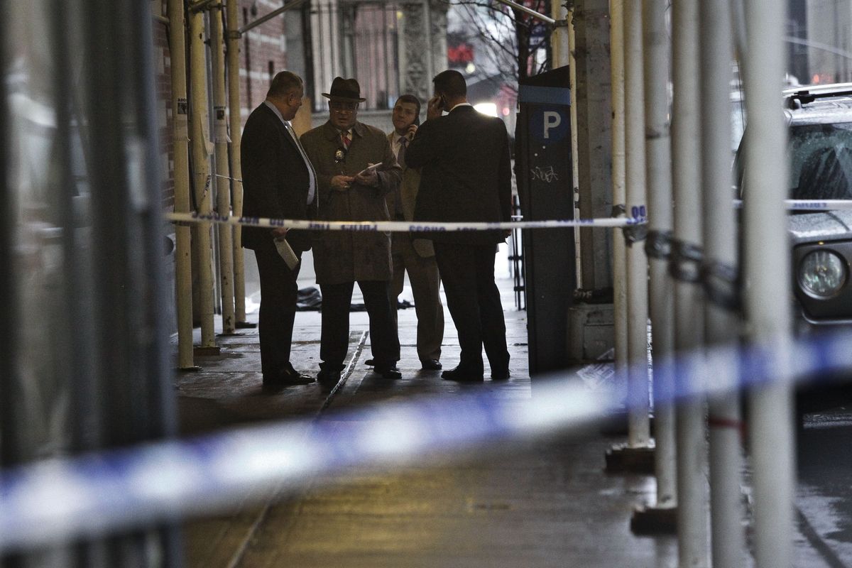 Police investigate the scene where a man was fatally shot in the back of the head in New York on Monday, Dec. 10, 2012. Authorities said the man was shot outside a school near Columbus Circle in Manhattan, lying mortally wounded in a pool of blood as the suspect escaped with a getaway driver. (Bebeto Matthews / Associated Press)