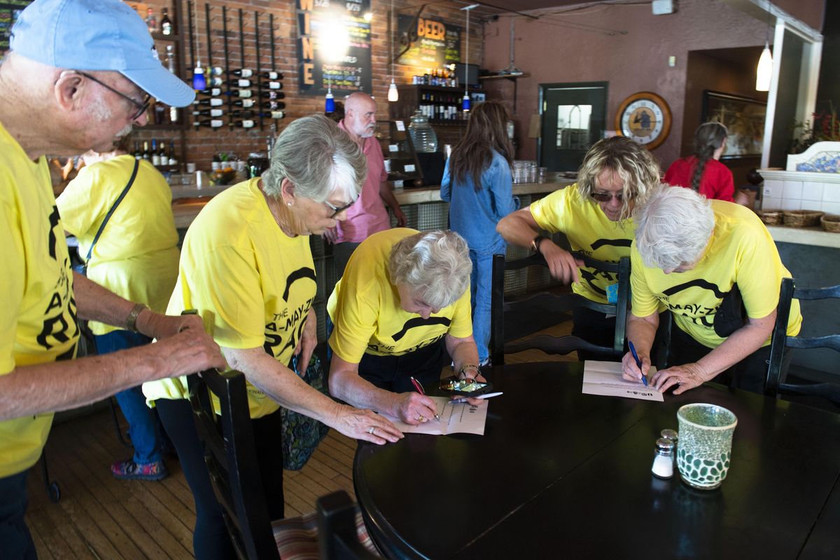 At Lindaman’s Gourmet-to-Go, A-MAY-Zing Race teams quickly fill out a task sheet that includes listing prices of wine, buying a cookie and asking staff questions about the origins of the restaurant. (Colin Mulvany / The Spokesman-Review)