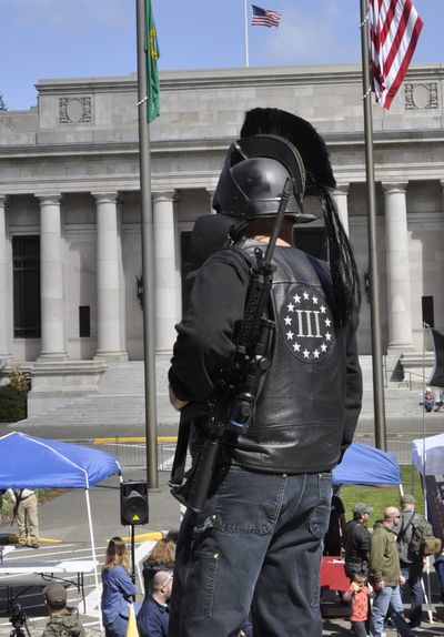 A protester at a 2018 Second Amendment rally on the steps of the Legislative Building in Olympia sports a semiautomatic rifle, black leather jacket and a replica of a Spartan helmet.  (Jim Camden/For The Spokesman-Review)
